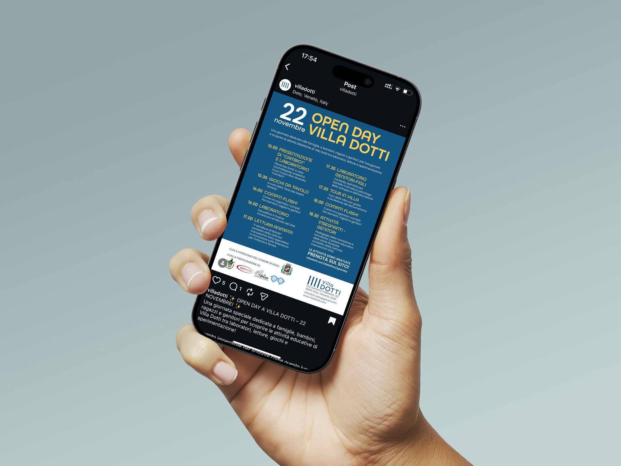 Una mano tiene un telefono con il post dell’Open Day